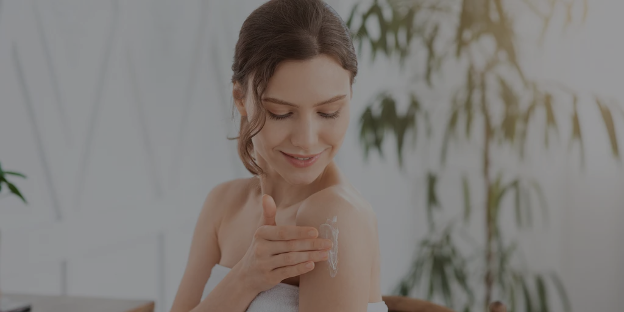 Woman applying cream to her arm with a blurred indoor background


